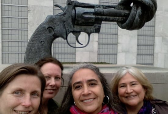 four female academics pose in from of an sculpture of a gun with its barrel tied up